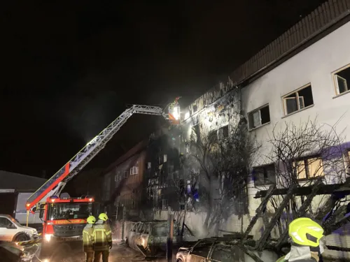 Feuerwehrleute stehen vor einem verbrannten Haus